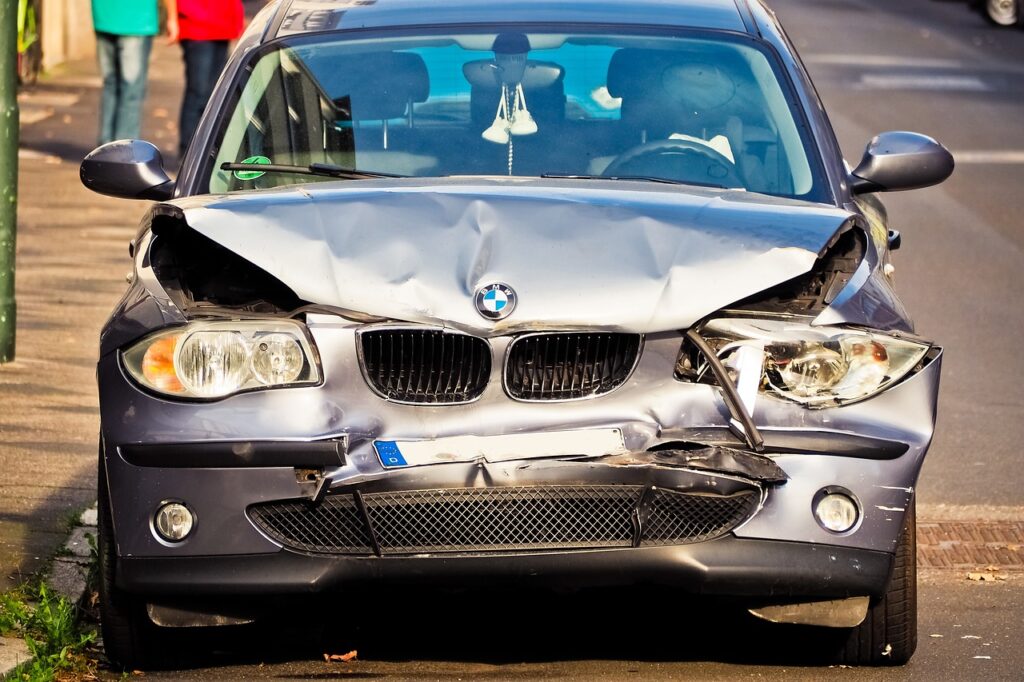 Car accident scene with a damaged vehicle being inspected at a repair shop, highlighting the importance of not releasing the vehicle to the insurance company before settling a claim to ensure fair compensation.